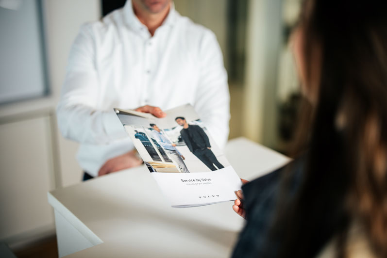 Verkoper geeft een blad aan klant